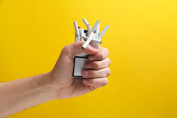 Stop smoking. Man holding pack with broken cigarettes on yellow background, closeup