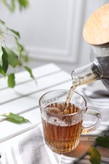 Pouring hot tea into cup on table, closeup