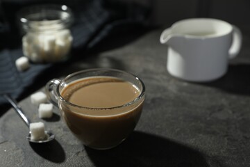 Tasty coffee with milk in cup and sugar cubes on grey table, closeup