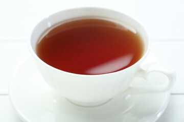 Aromatic tea in cup on white table, closeup