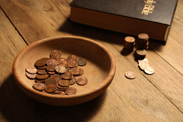 Donate and give concept. Bowl with coins and Bible on wooden table, closeup