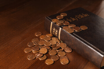 Donate and give concept. Coins and Bible on wooden table