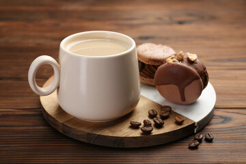Cup of coffee and delicious macarons on wooden table