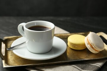 Tray with hot coffee in cup and macarons on dark textured table, closeup