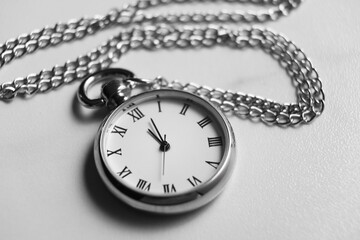 Silver pocket clock with chain on light table, closeup