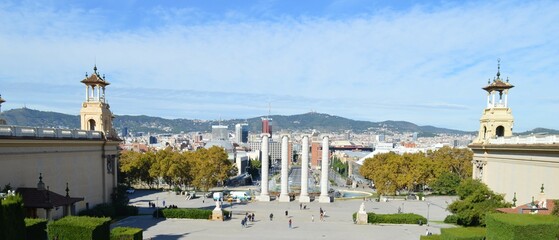 Obraz premium View from the National Palace of Barcelona, ​​panorama of the city and view of the mountains - historical sights of Catalonia - a magical fountain, a palace and urban buildings