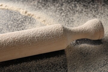 Scattered flour and rolling pin on table, closeup