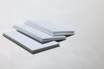 Blank business cards on light grey textured table, closeup. Mockup for design