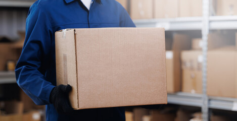 Banner center logistic and delivery. Worker in blue uniform hold cardboard box on background...