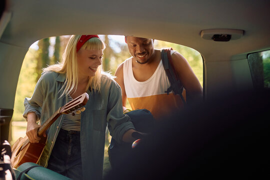 Happy couple of campers packing up equipment into van trunk. - Powered by Adobe
