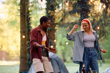 Carefree couple dancing and having fun while camping in nature.