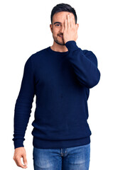 Fototapeta premium Young handsome man wearing casual clothes covering one eye with hand, confident smile on face and surprise emotion.