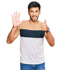 Fototapeta premium Young handsome man wearing casual clothes showing and pointing up with fingers number six while smiling confident and happy.