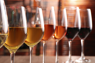 Different tasty wines in glasses against blurred background