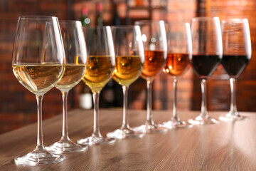 Different tasty wines in glasses on wooden table