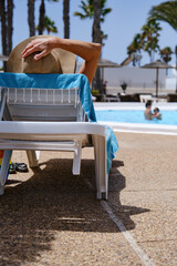Unrecognizable man sitting on deckchair near pool