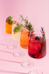 Colourful alcoholic cocktails in glasses on pink background