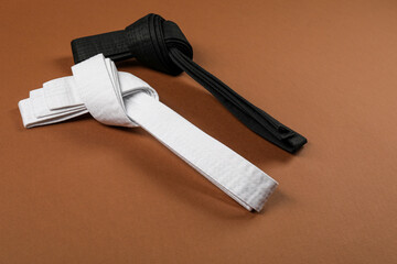 White and black karate belts on brown background