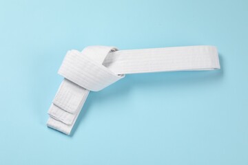 Obraz premium White karate belt on light blue background, top view