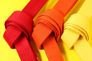 Colorful karate belts on yellow background, flat lay © New Africa
