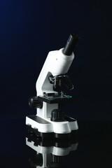 Modern medical microscope on black mirror surface