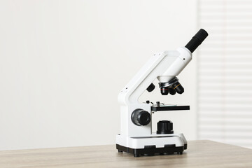 Modern medical microscope on wooden table indoors