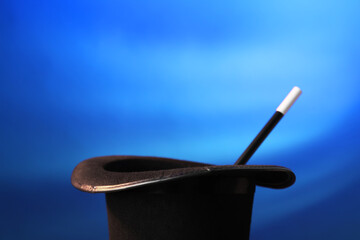 Magician's hat and wand on blue background, space for text