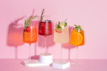 Colourful summer alcoholic cocktails with ice on pink background