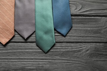 Different neckties on black wooden table, flat lay. Space for text