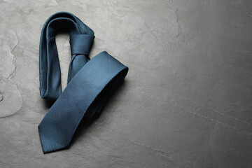 One blue necktie on grey textured table, top view. Space for text