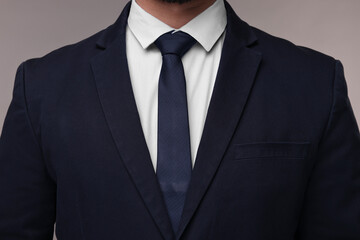 Businessman in suit and necktie on grey background, closeup