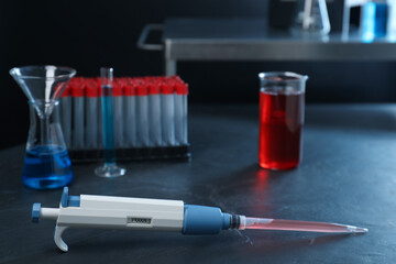 Laboratory analysis. Micropipette and different glassware on black table