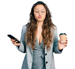 Young hispanic girl using smartphone and drinking a cup of coffee making fish face with mouth and...