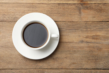 Cup of aromatic coffee on wooden table, top view. Space for text