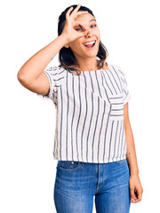 Young woman wearing casual clothes doing ok gesture with hand smiling, eye looking through fingers with happy face.