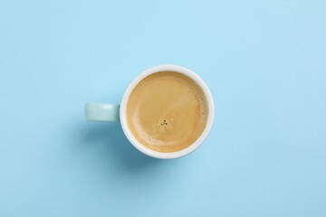 Aromatic coffee in cup on light blue background, top view