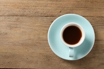 Tasty coffee in cup on wooden table, top view. Space for text