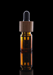 One brown bottle with tincture on mirror surface against black background