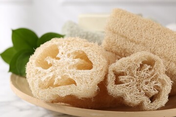 Loofah sponges and green leaves on table, closeup