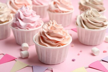 Delicious birthday cupcakes, bunting flags, marshmallows and sprinkles on pink background, closeup