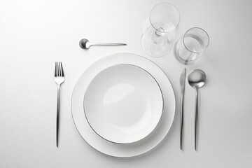 Stylish setting with cutlery and glasses on white textured table, flat lay