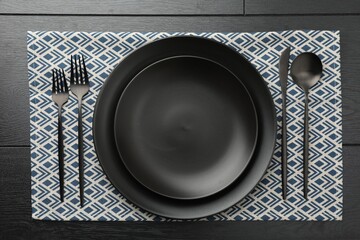 Stylish setting with cutlery and plates on black wooden table, flat lay