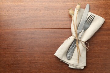 Stylish setting with cutlery and napkin on wooden table, top view. Space for text