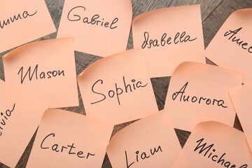 Paper stickers with different names on wooden background, flat lay. Choosing baby's name