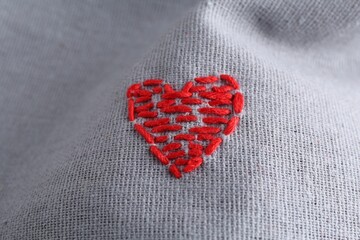 Embroidered red heart on gray cloth, above view