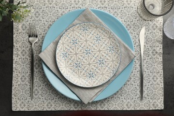 Stylish setting with cutlery, glasses and plates on black table, flat lay
