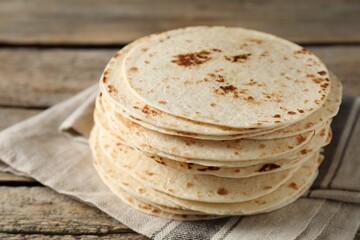 Stack of tasty homemade tortillas on wooden table, closeup