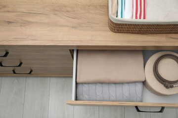 Chest of drawers with different folded clothes and accessories indoors, top view