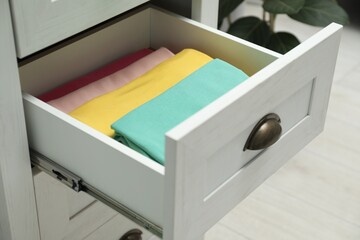 Chest of drawers with different folded clothes indoors