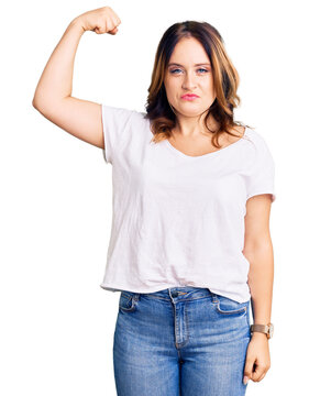 Young beautiful caucasian woman wearing casual white tshirt strong person showing arm muscle, confident and proud of power